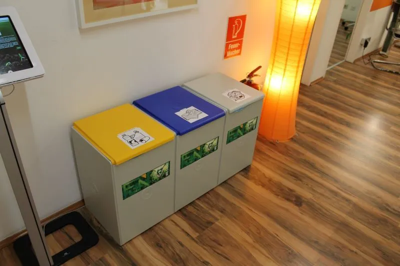 M&uuml;lltrennsystem im FUN. Drei Container mit unterschiedlich farbigen Deckeln.